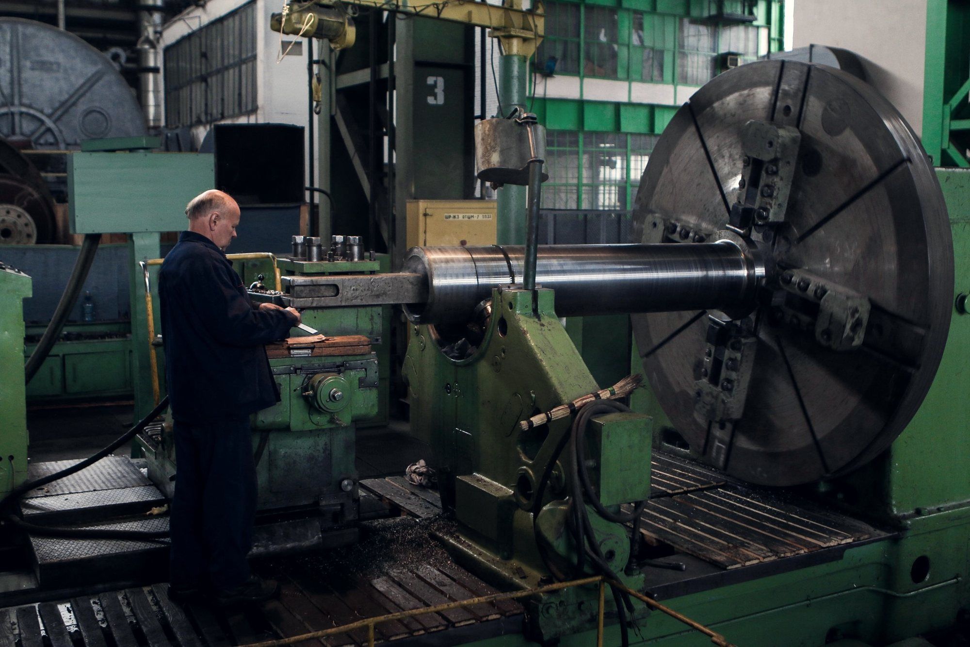 Large lathe in a plant hall with an operator at the controls